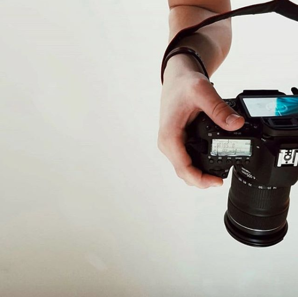 about-page-hand-holding-camera-against-white-background